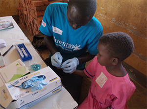 Health worker taking a finger prick blood test in Mayuge District, Uganda